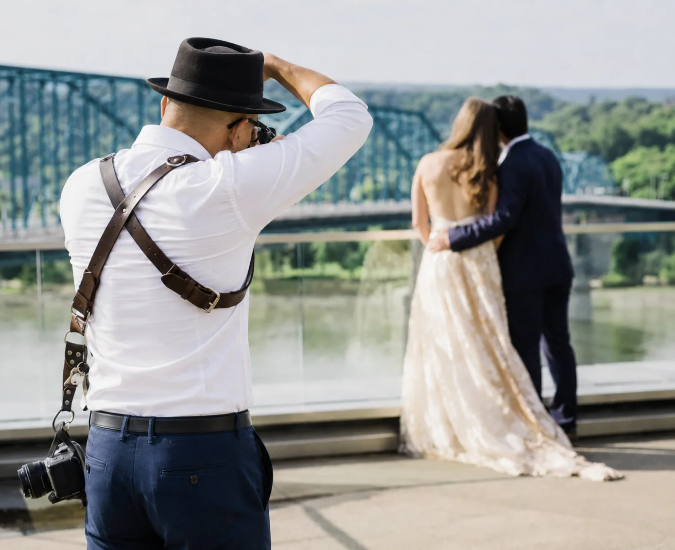 Arman photographing a couple embracing on a bridge over a river
