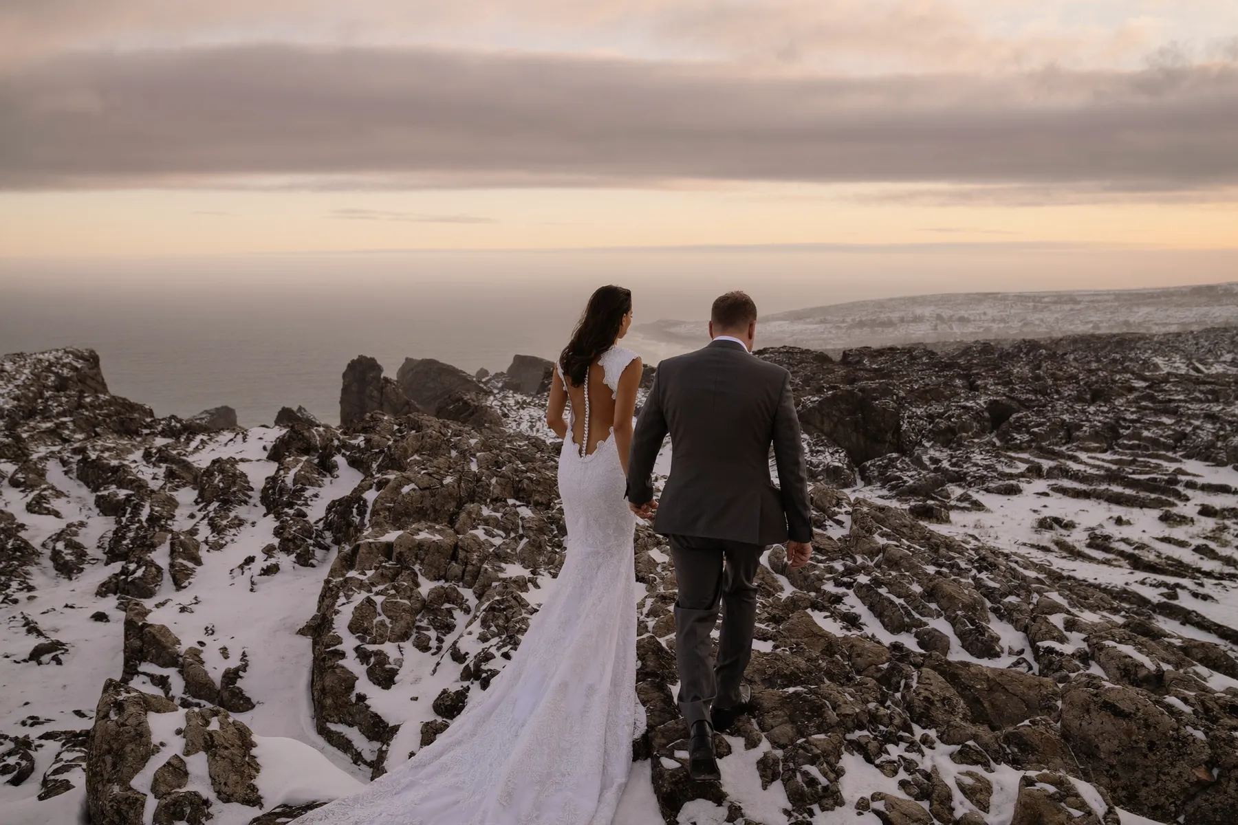 Couple walking a snowy rocky shoreline at sunset in Parc national du Bic