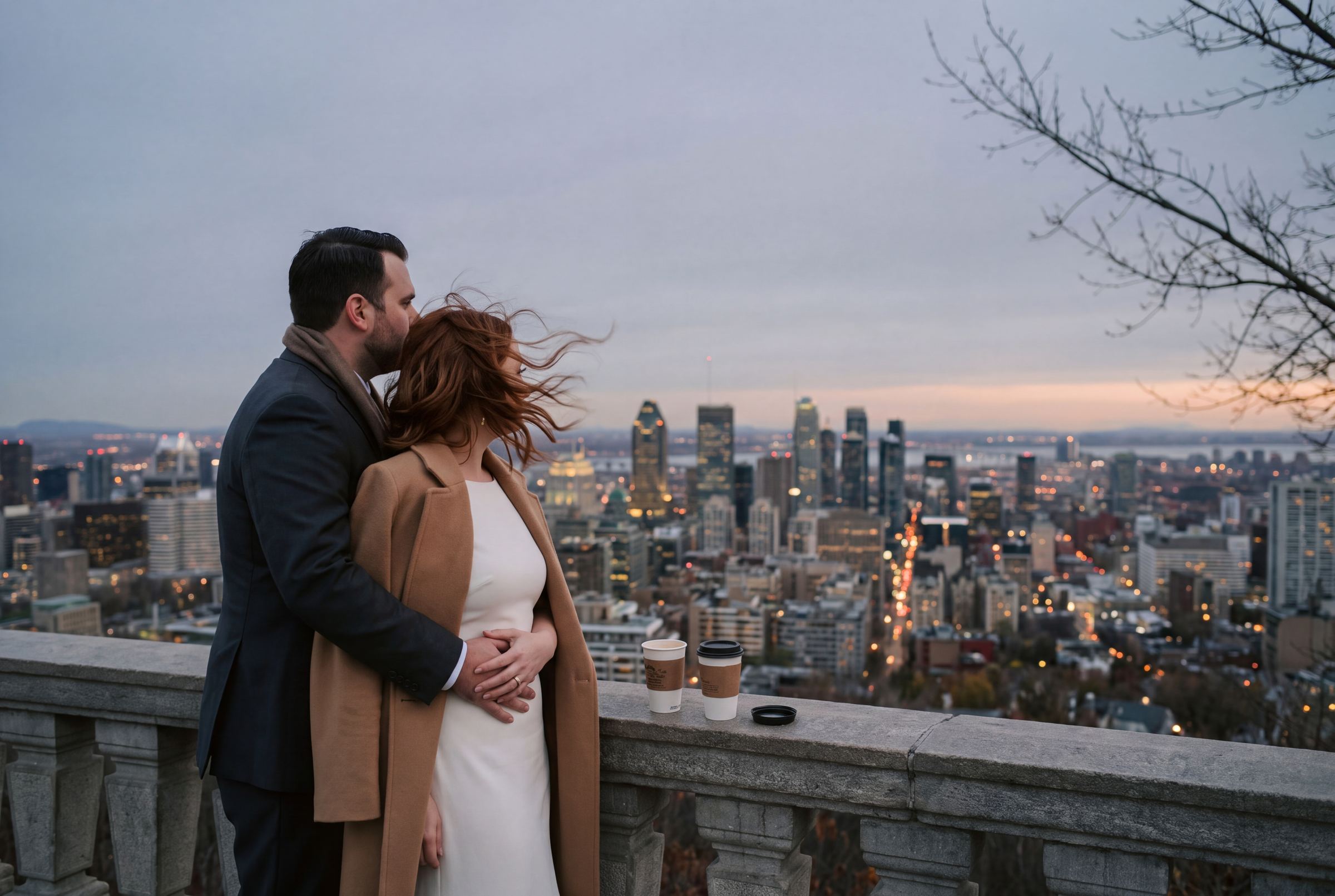 Couple embracing on Mont-Royal with the Montréal skyline behind them at dusk
