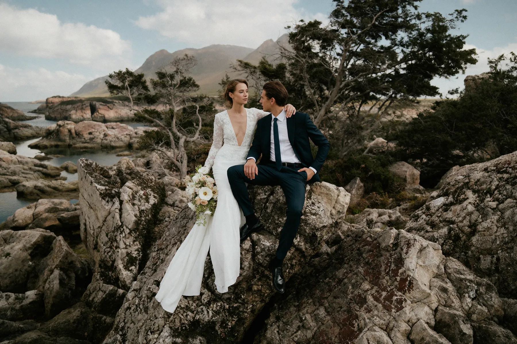 Couple seated on the rocks at Whytecliff Park with the islands beyond