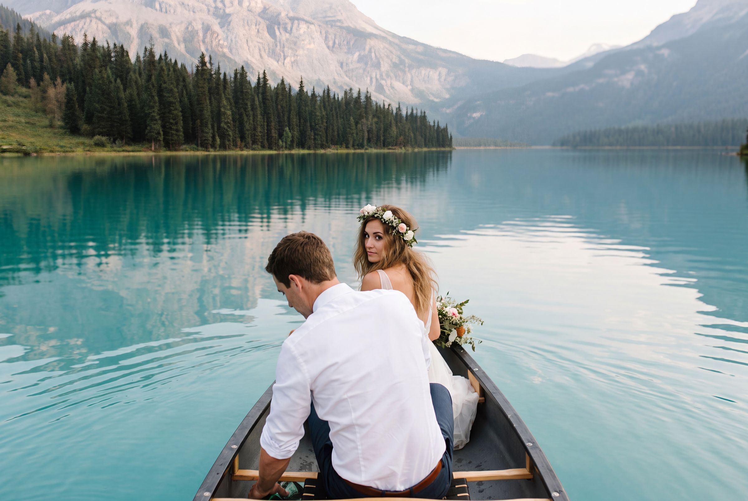 A couple in a canoe on the still turquoise water of a Banff lake at dawn