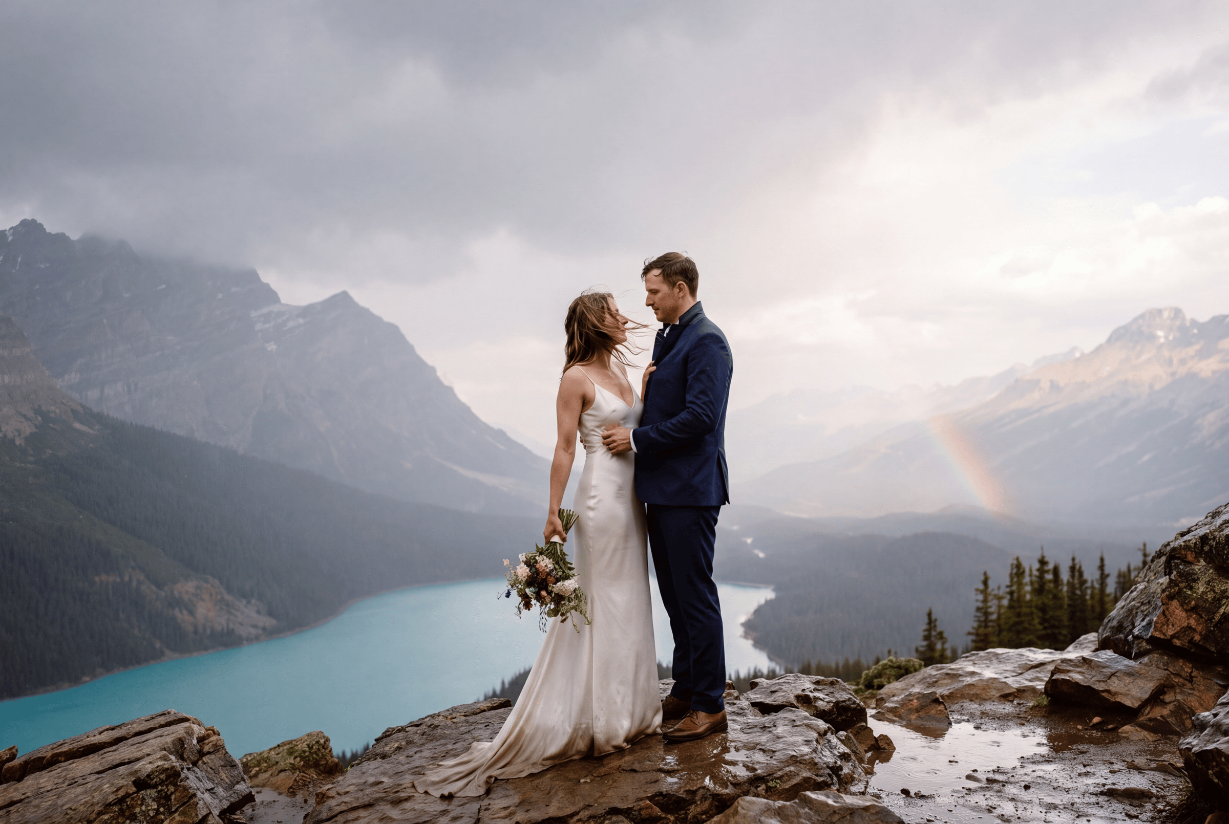 A couple on the rocks above a glacial lake in Banff National Park