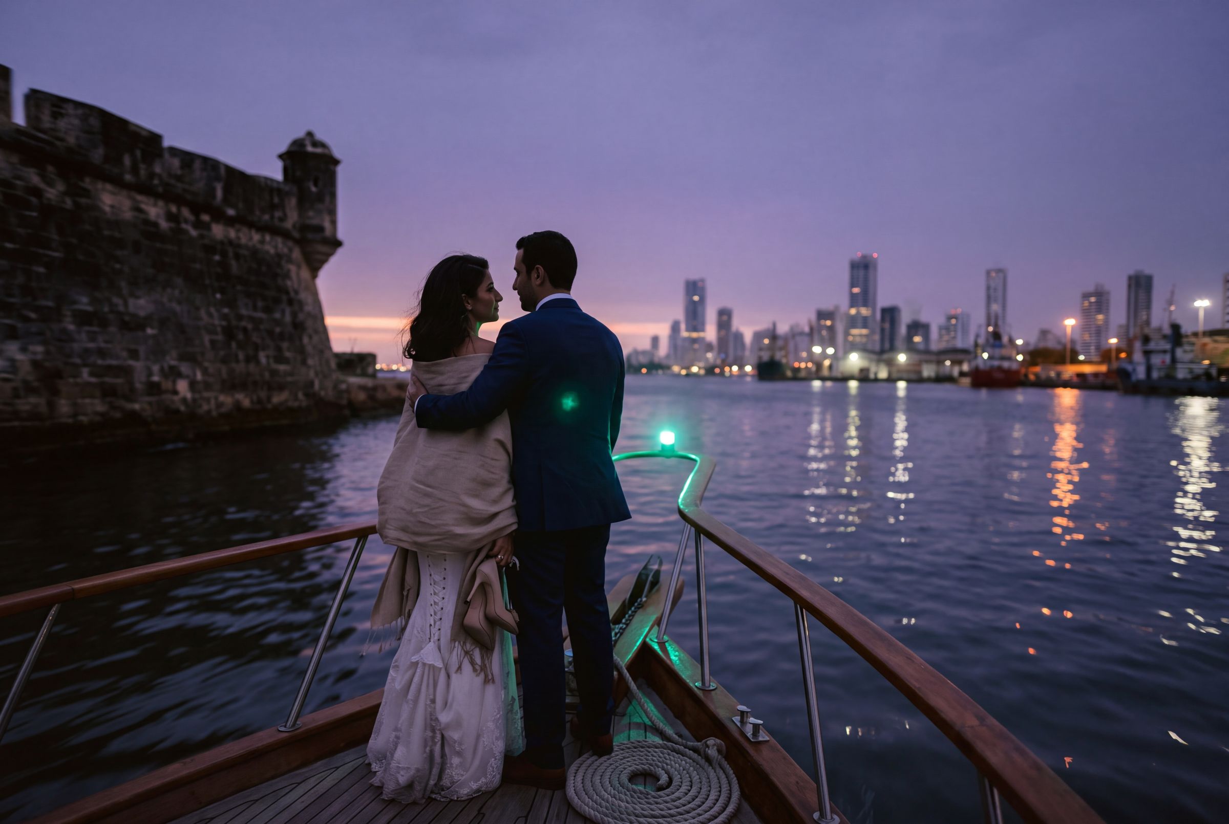 A couple on a wooden boat at dusk with the Cartagena skyline behind
