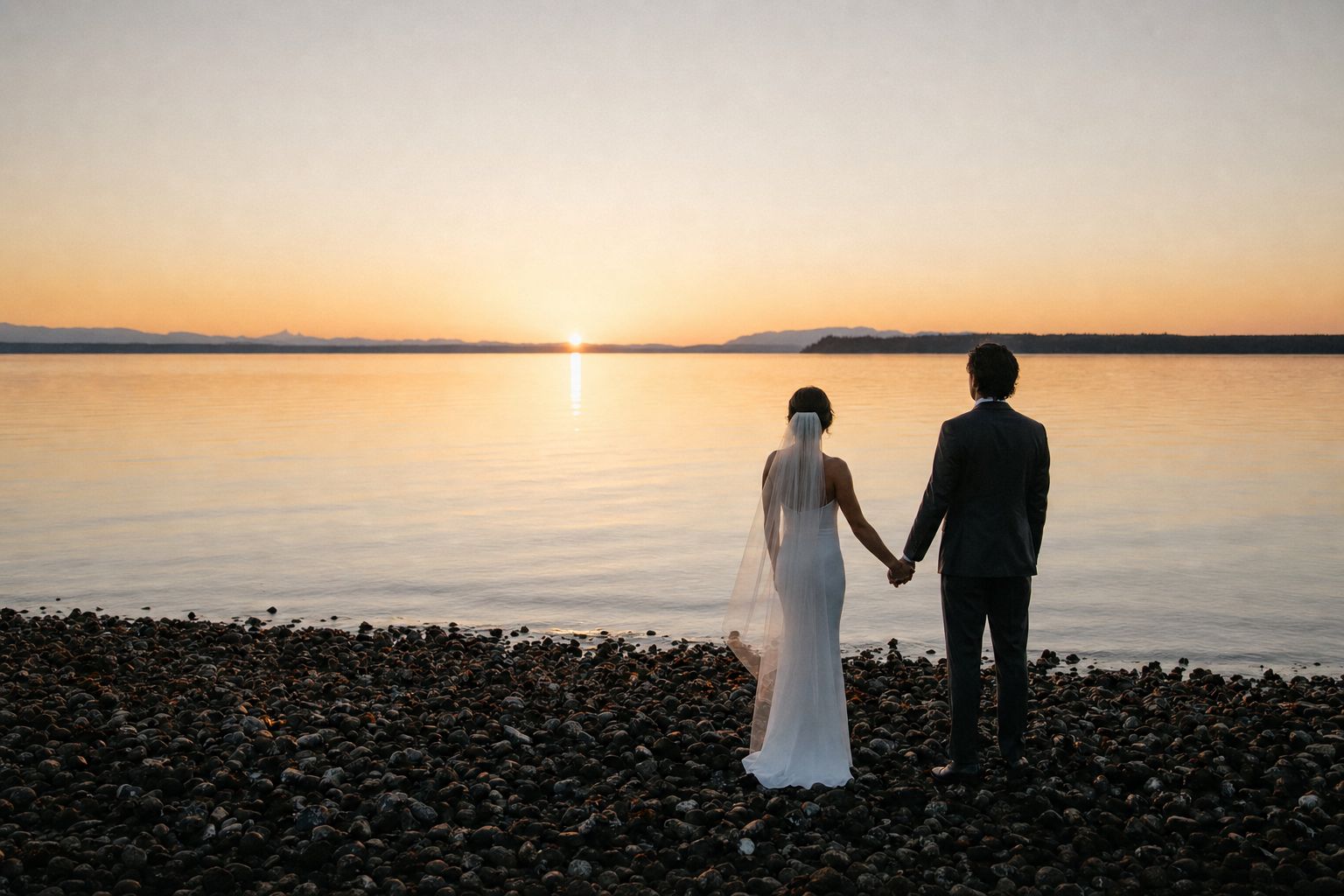 A couple on a driftwood beach at sunset on the east coast of Vancouver Island