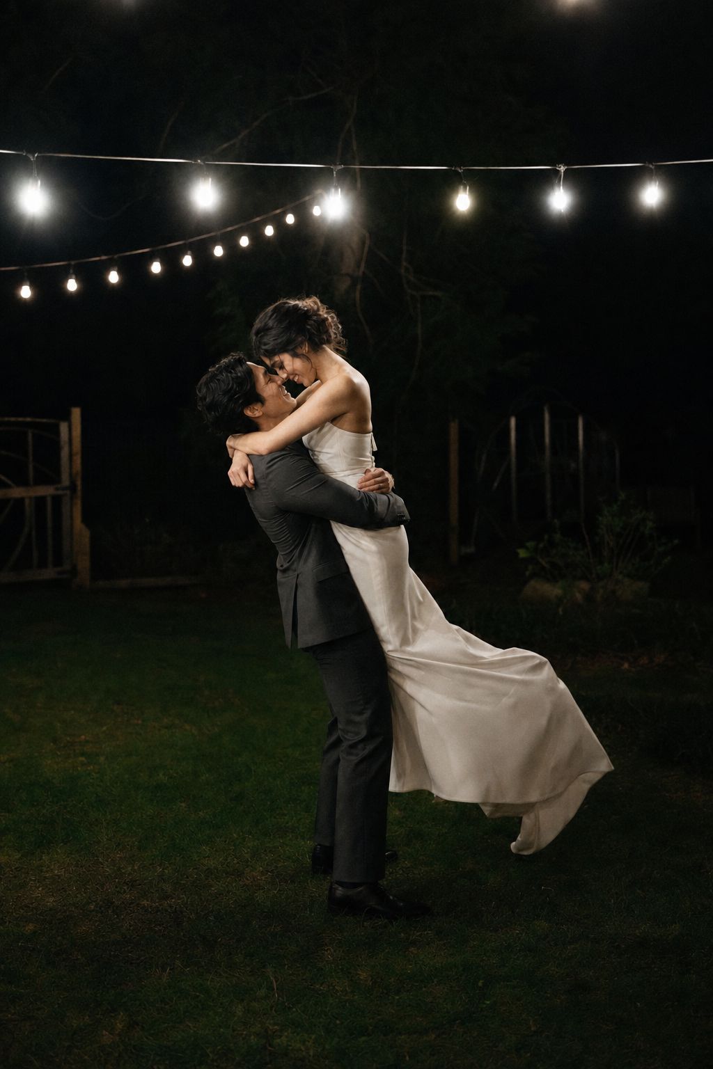 A couple dancing under string lights at night at the end of their Vancouver Island elopement
