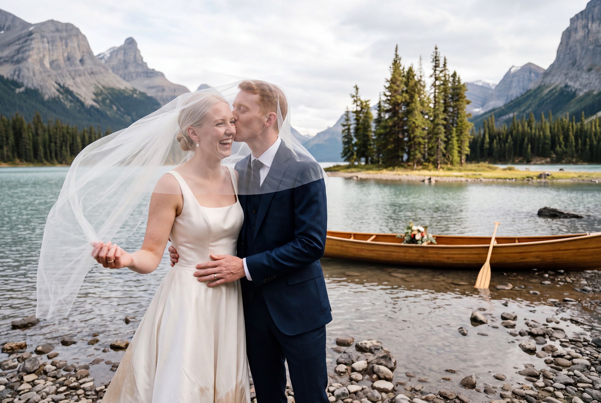 A couple beside a canoe on the shore of Maligne Lake with Spirit Island behind