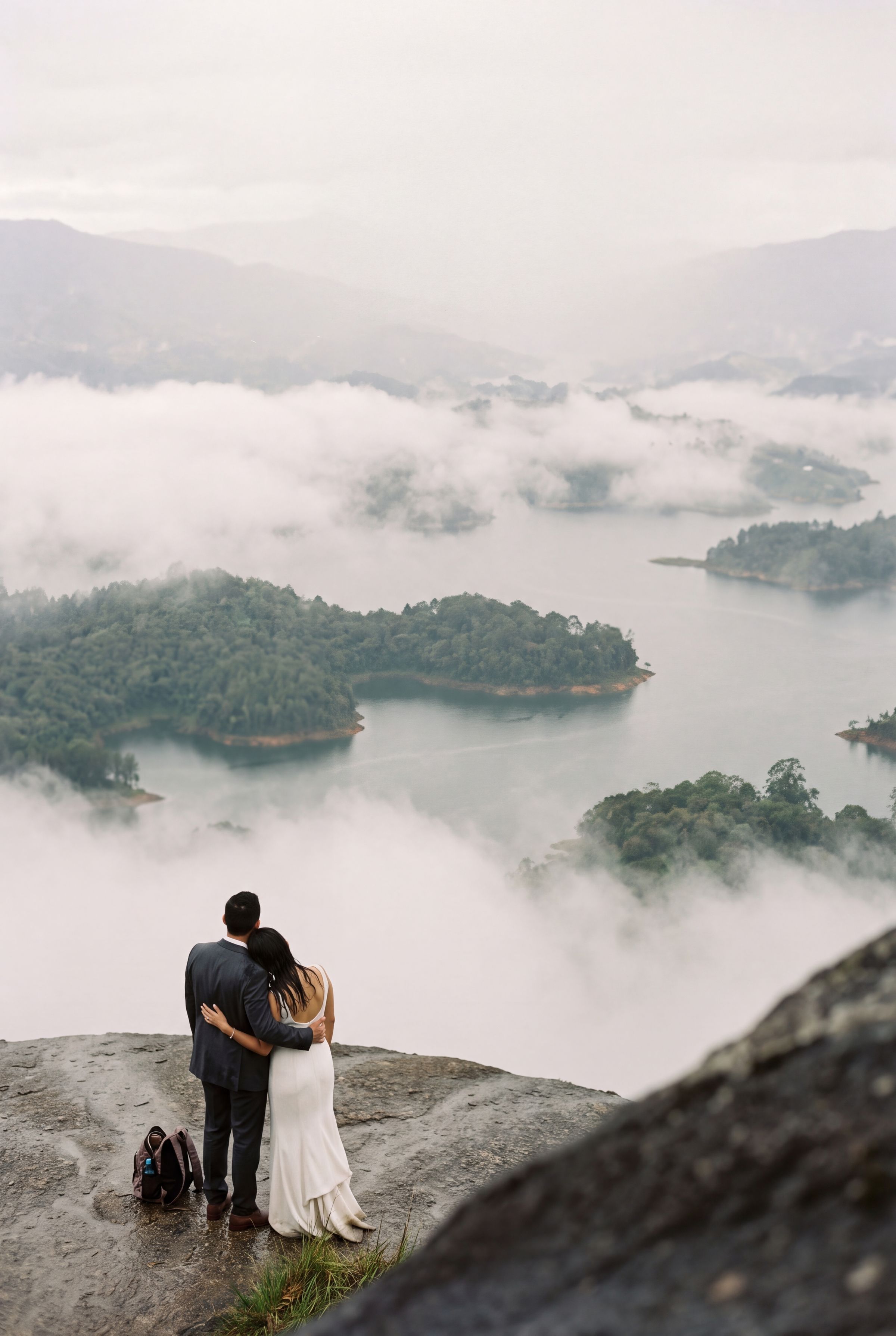 A couple on bare rock high above the flooded reservoir valley at Guatapé, Colombia