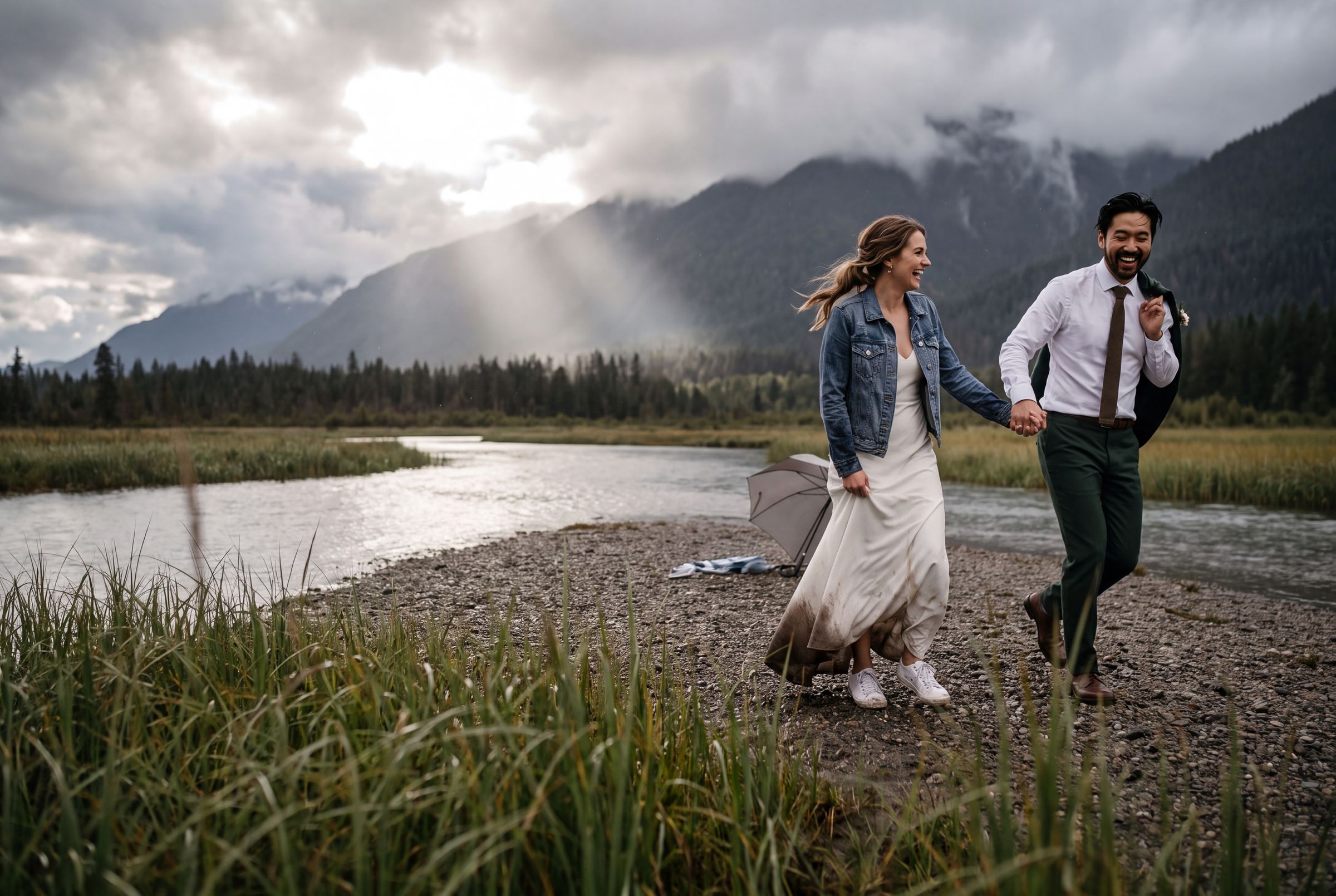 A couple running along a braided river below the mountains near Revelstoke