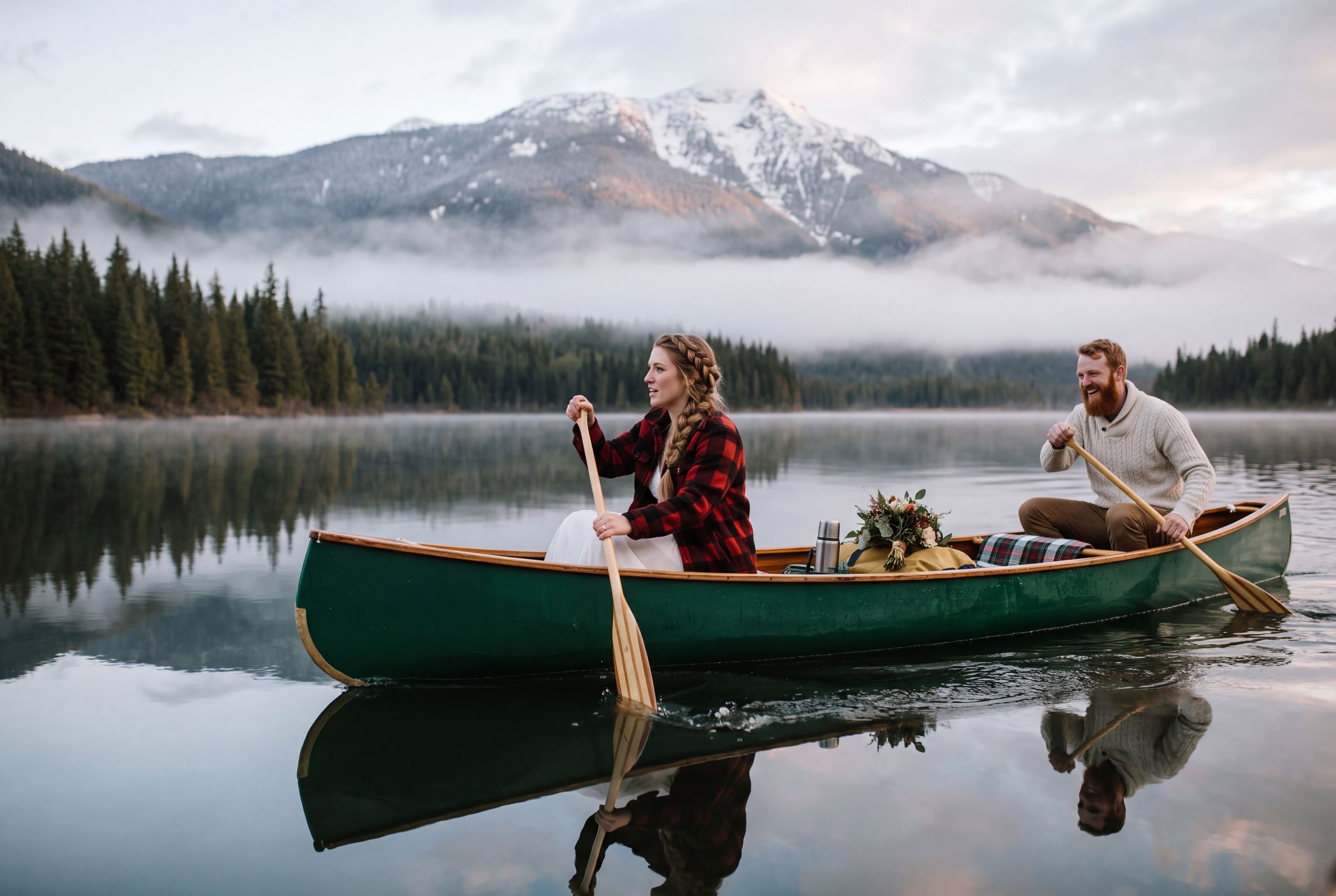 A couple in a canoe on a still misty lake in the mountains near Revelstoke