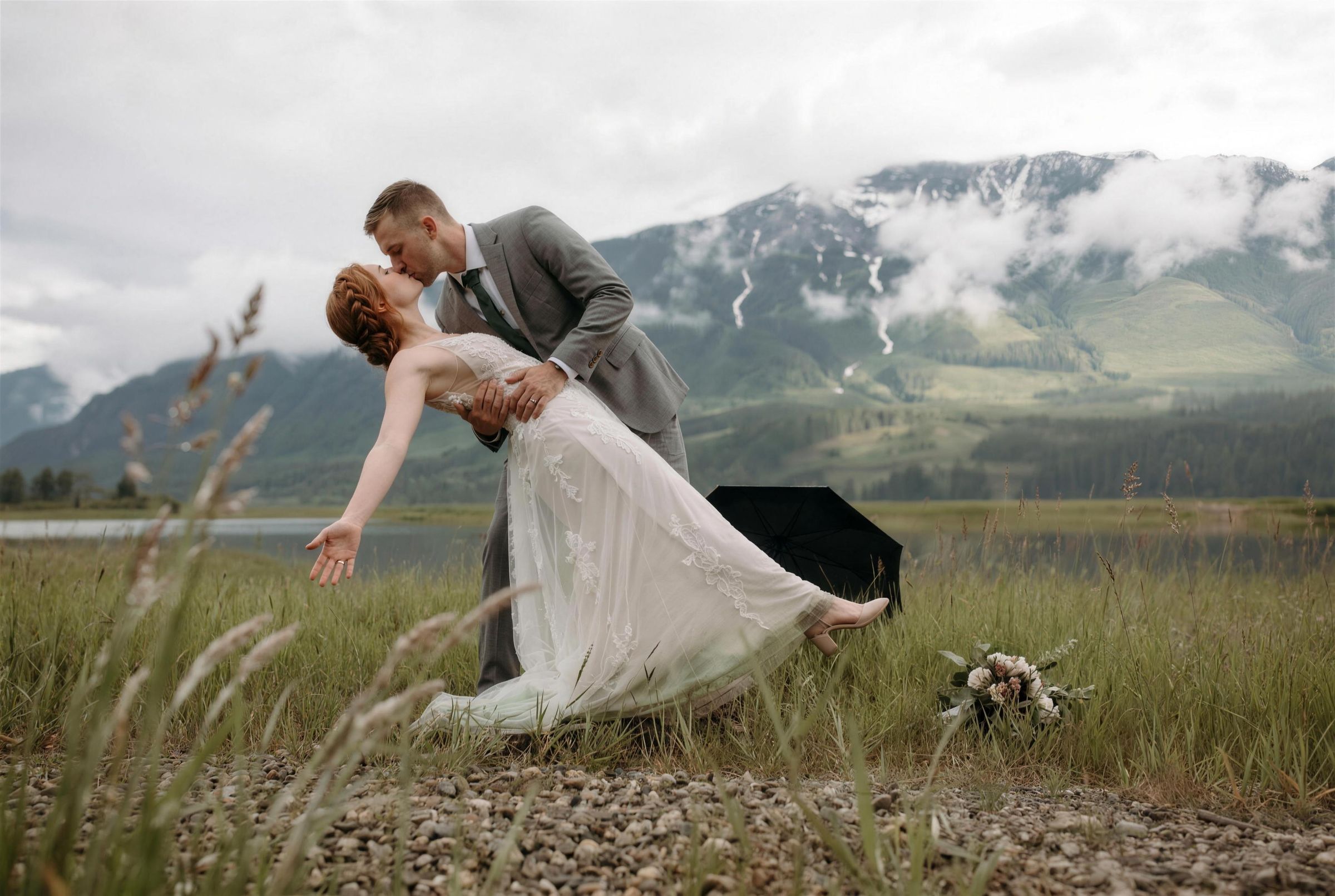 A couple lying in an alpine meadow with mountains behind them near Revelstoke