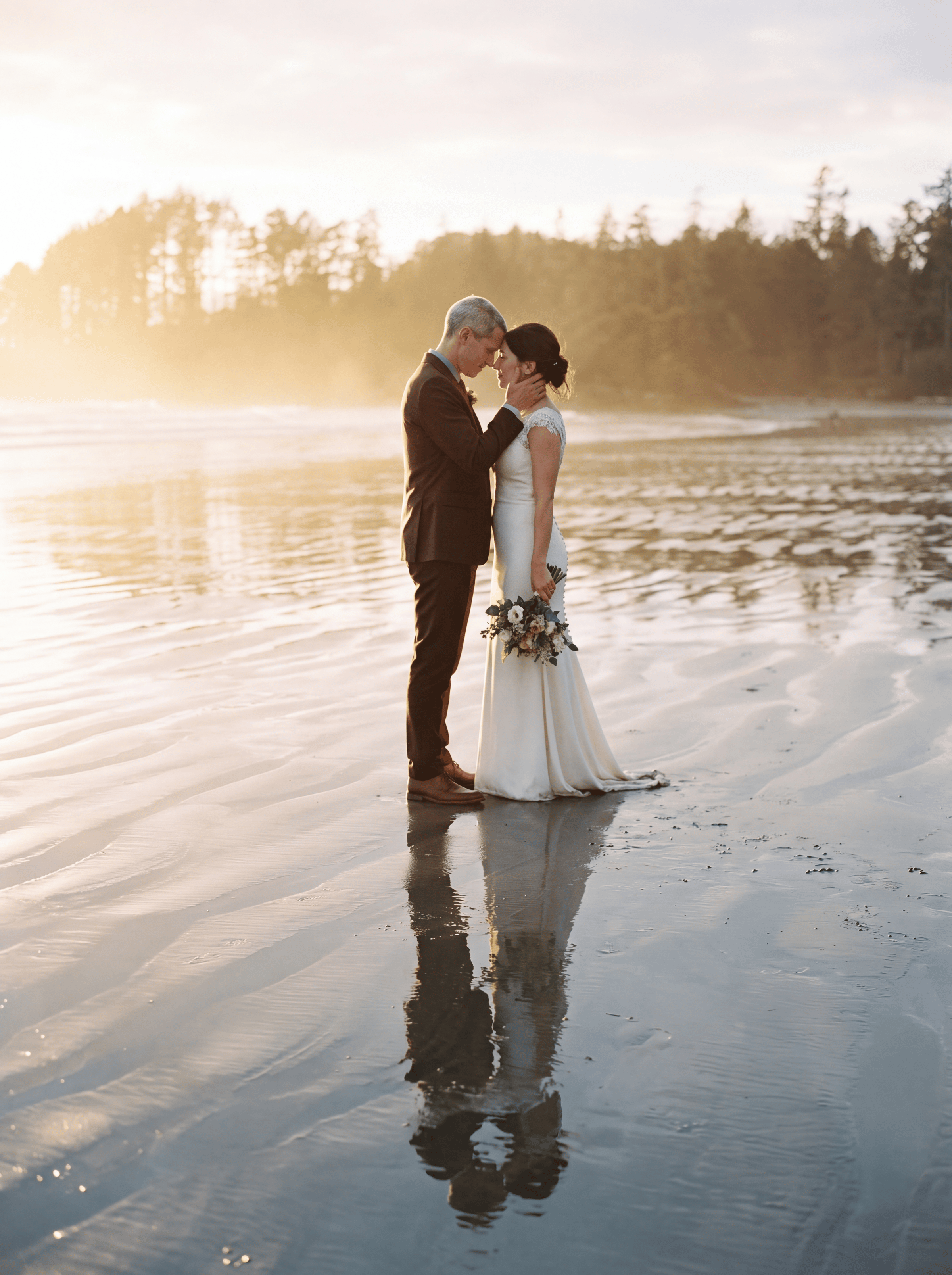 A couple walking a driftwood beach in the fog on Vancouver Island