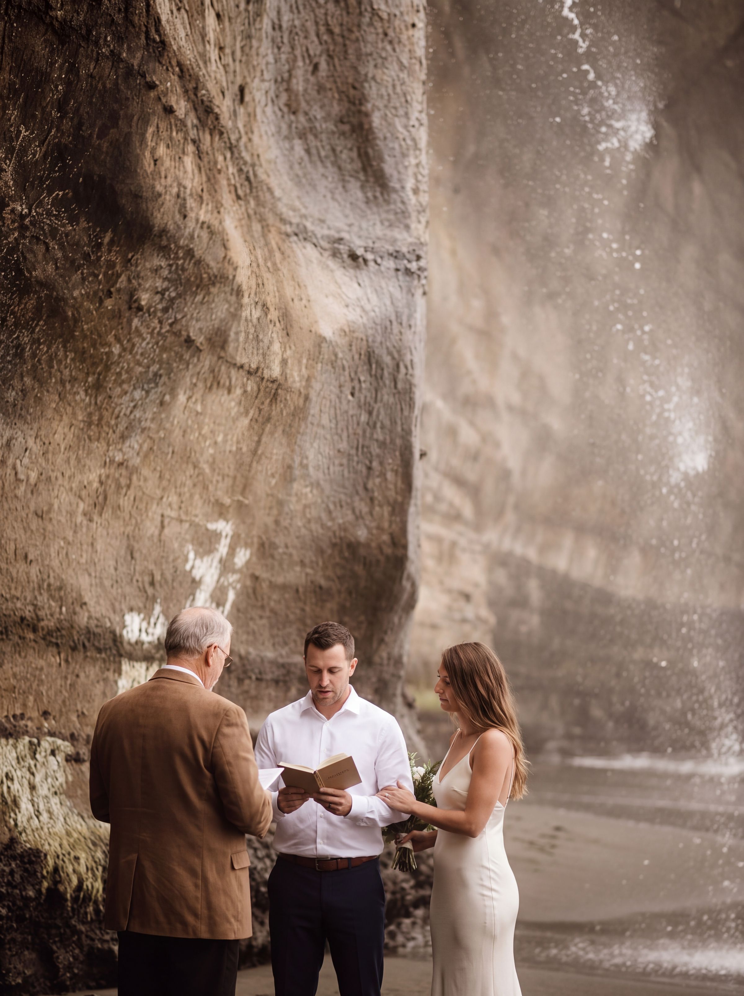 A couple on a rocky Pacific beach below rainforest cliffs on Vancouver Island at golden hour