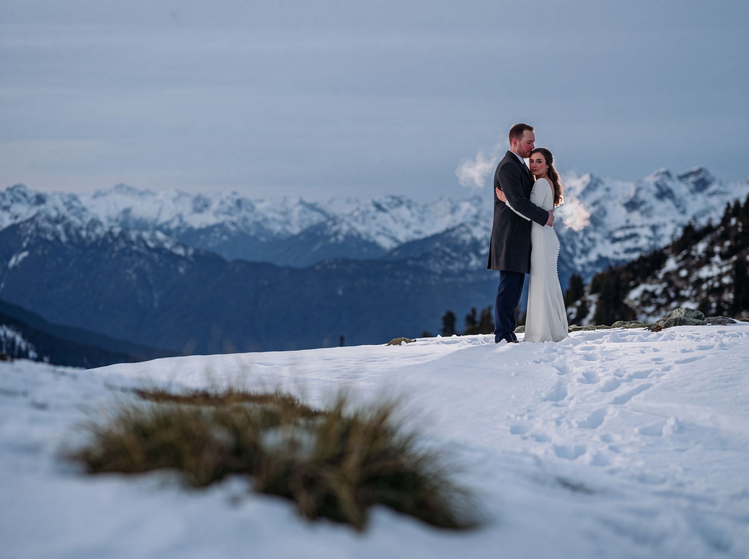 A couple on a snowy ridge above Whistler with cloud in the valley below