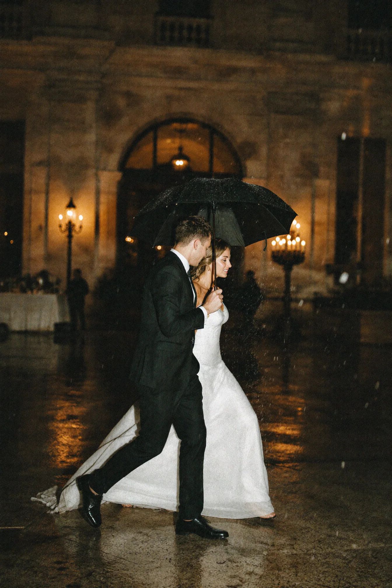 Couple under an umbrella on wet cobbles at night