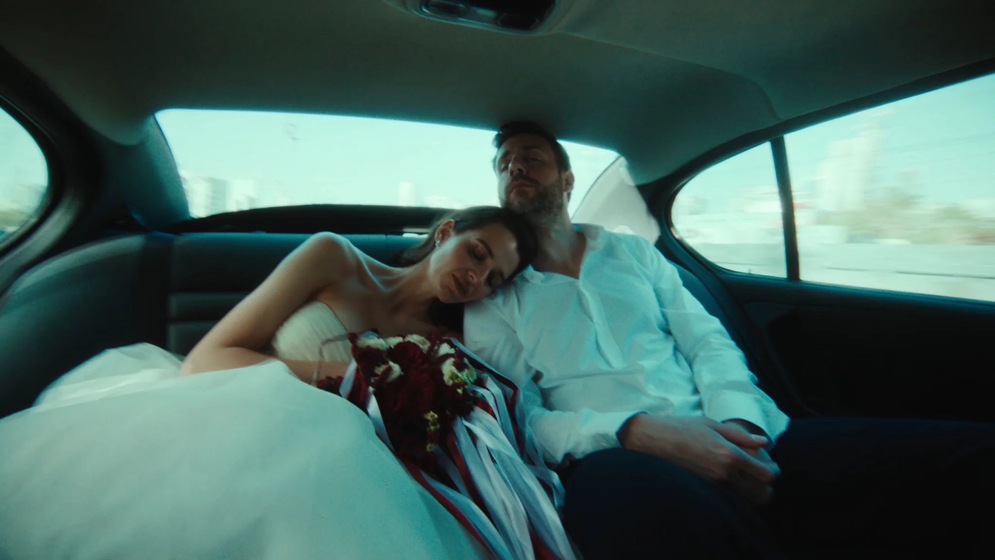 Couple resting together in the back seat of a car in teal evening light