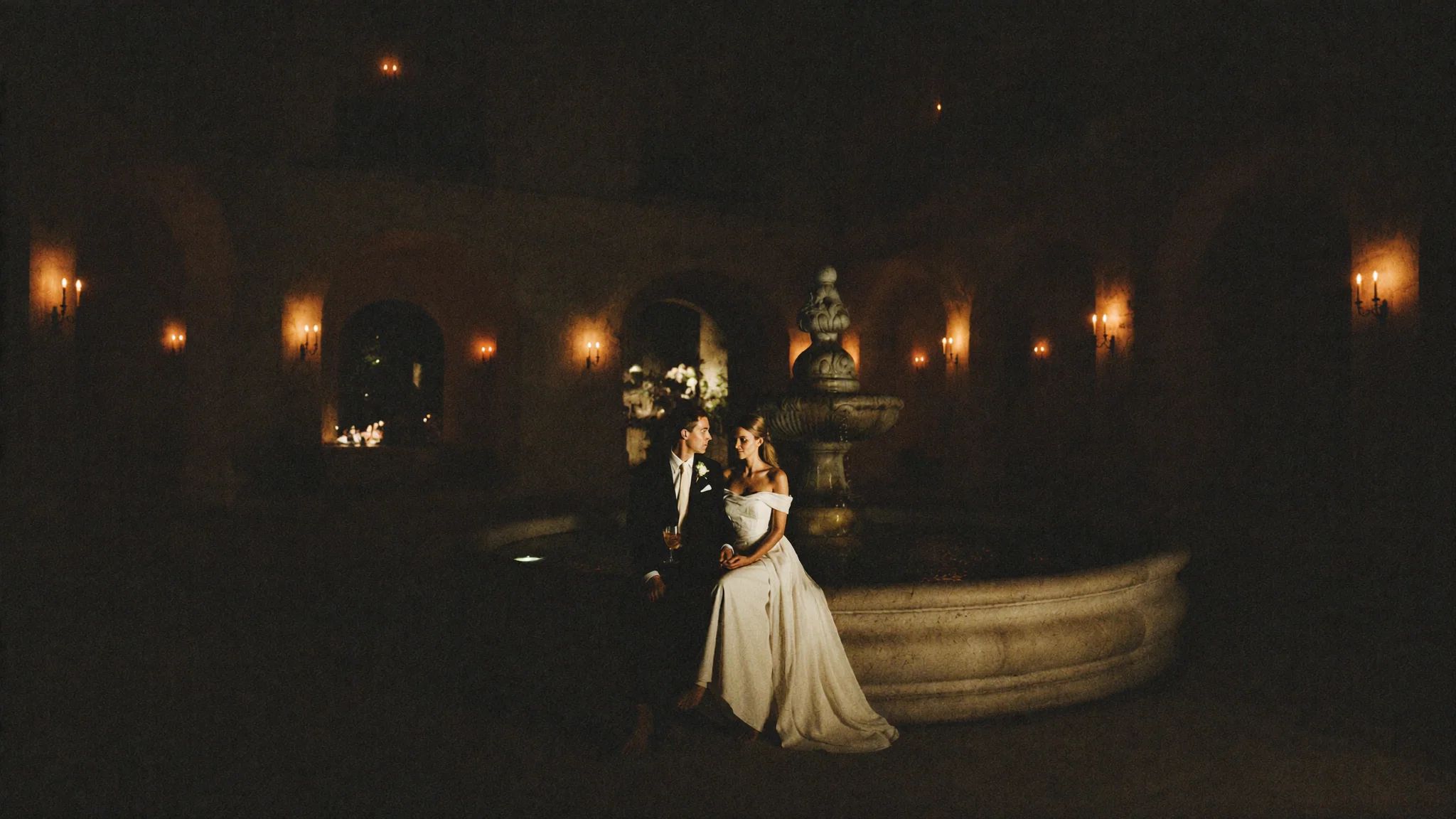 Bride walking a dark chapel aisle lined with candles