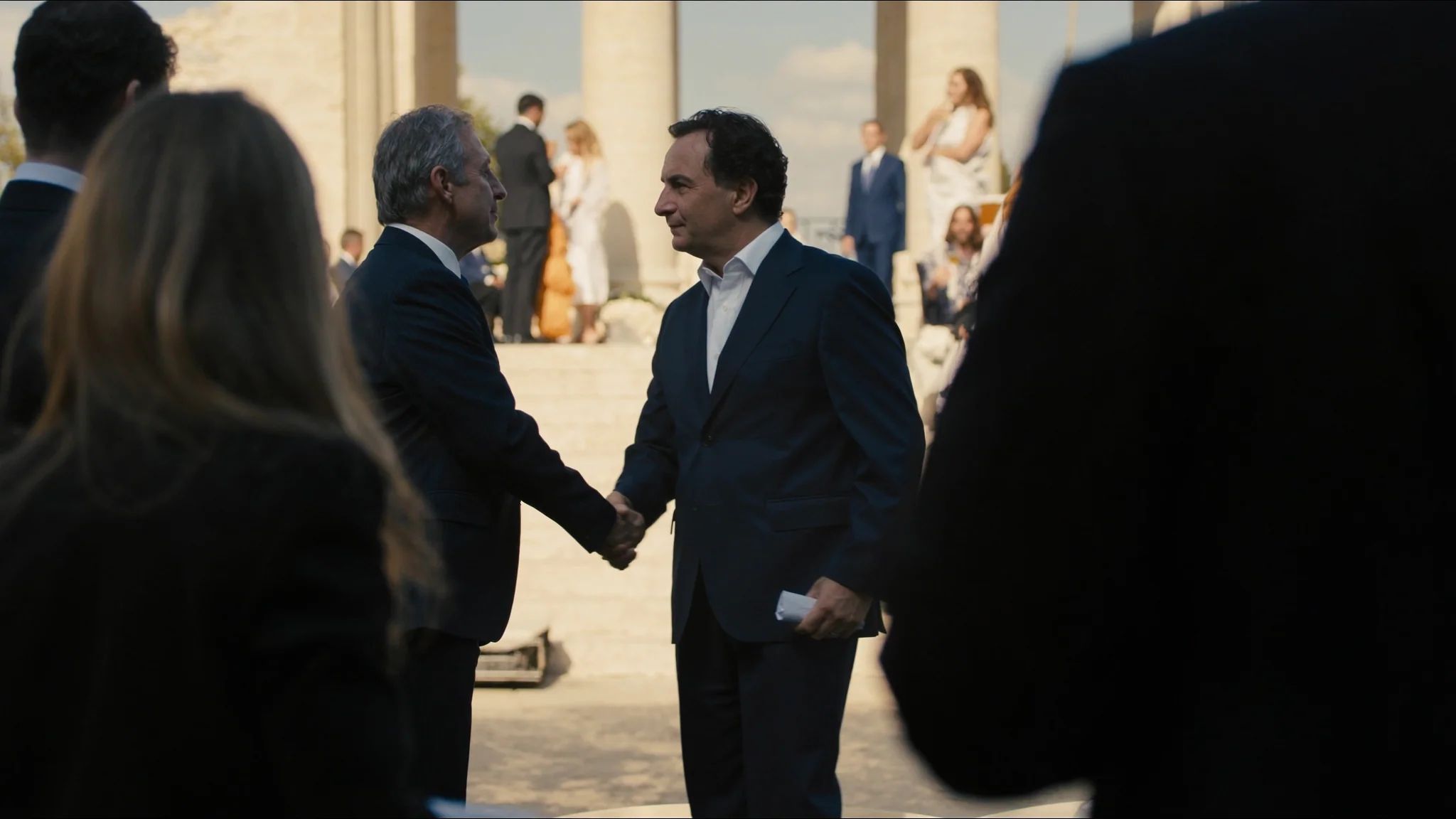 Two guests holding hands framed over a shoulder in the crowd