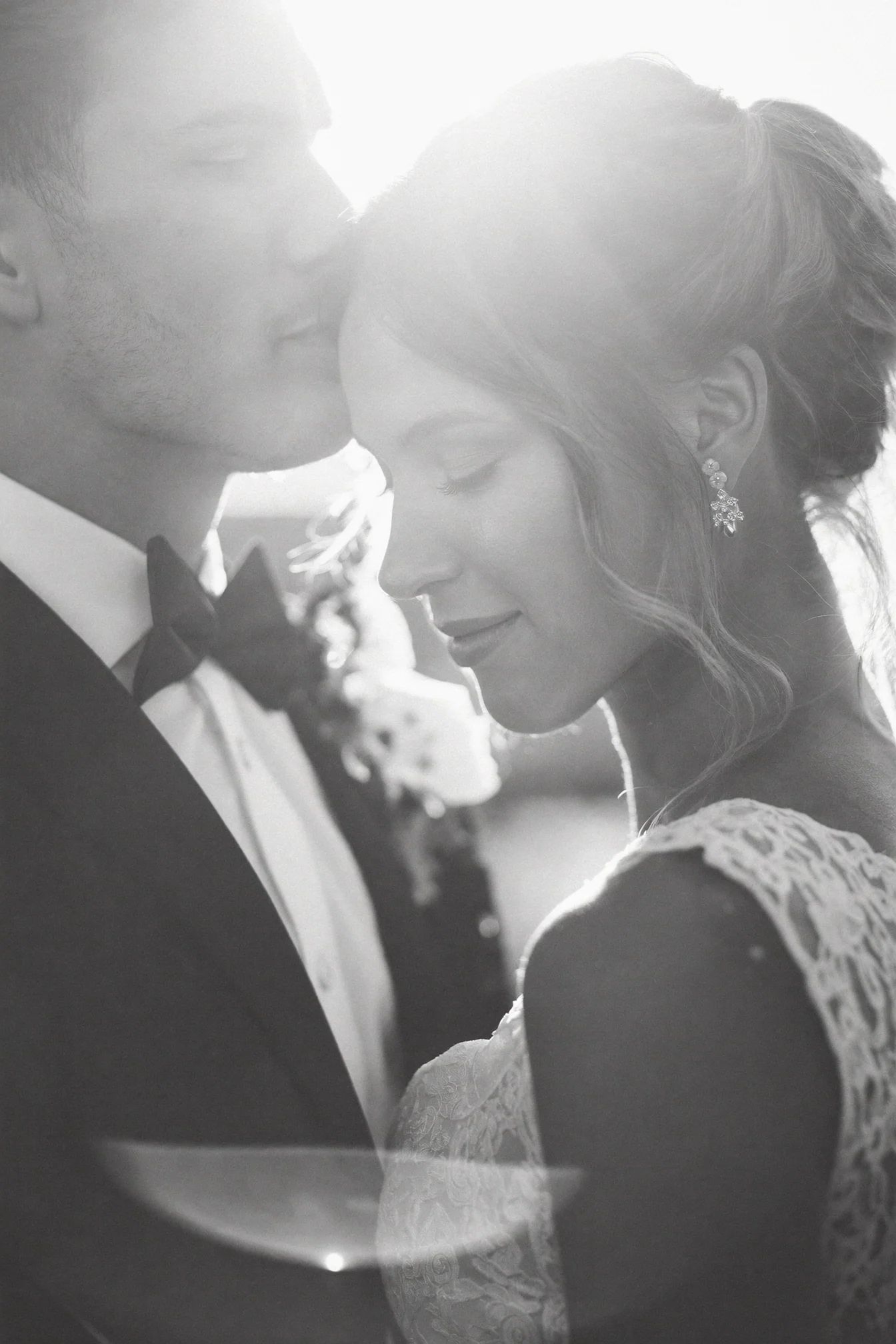 Backlit close portrait of a couple with their foreheads together