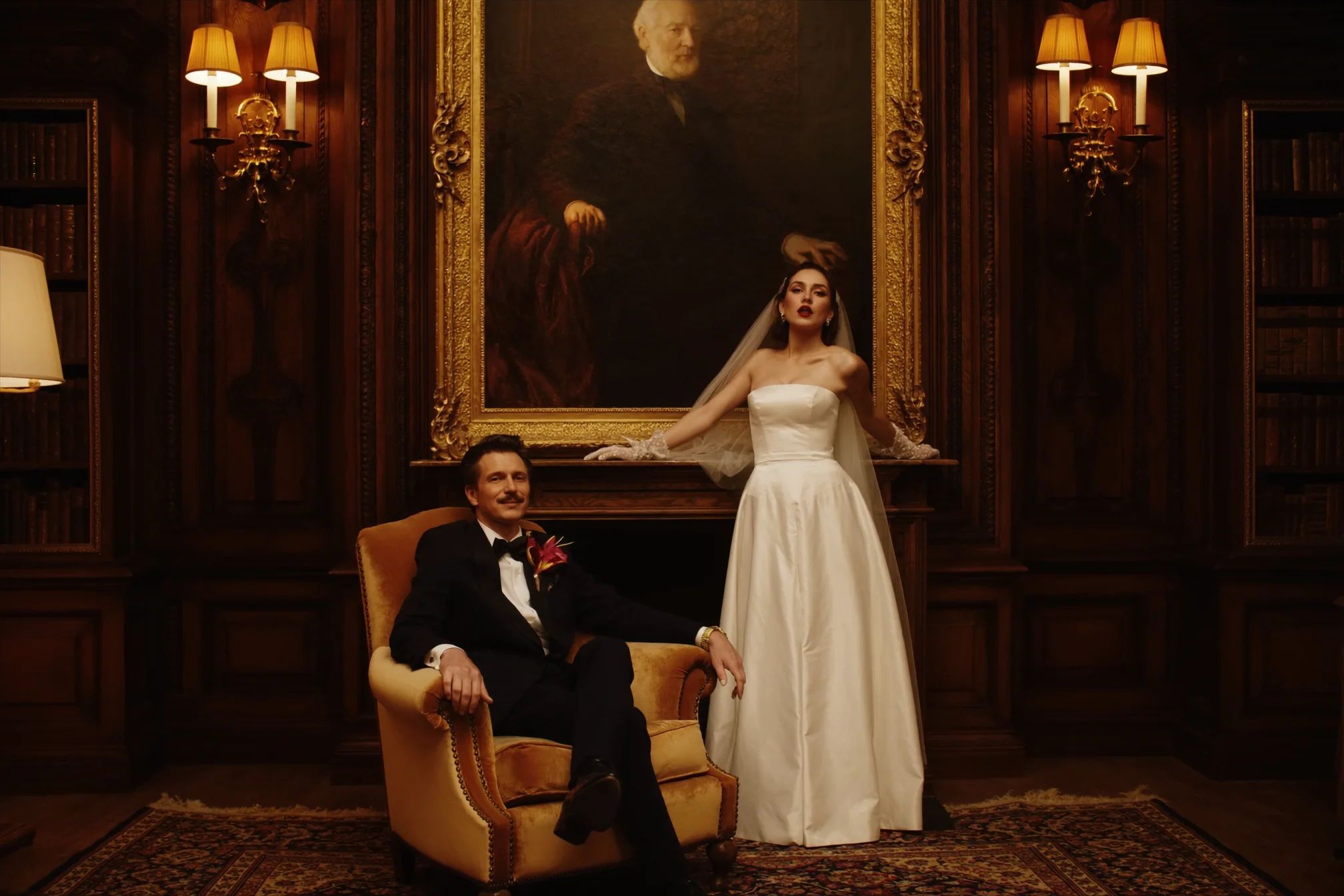 Couple in a wood-panelled library with the groom in a gold armchair
