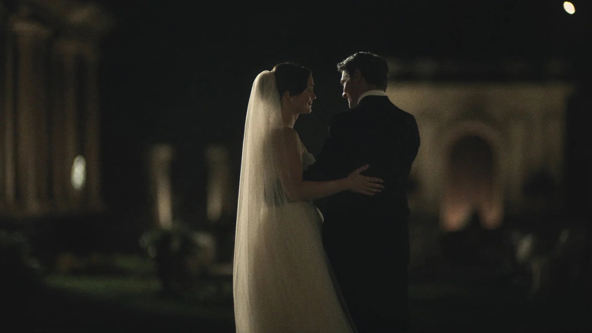 Couple embracing in a dim colonnade with light coming from the far end