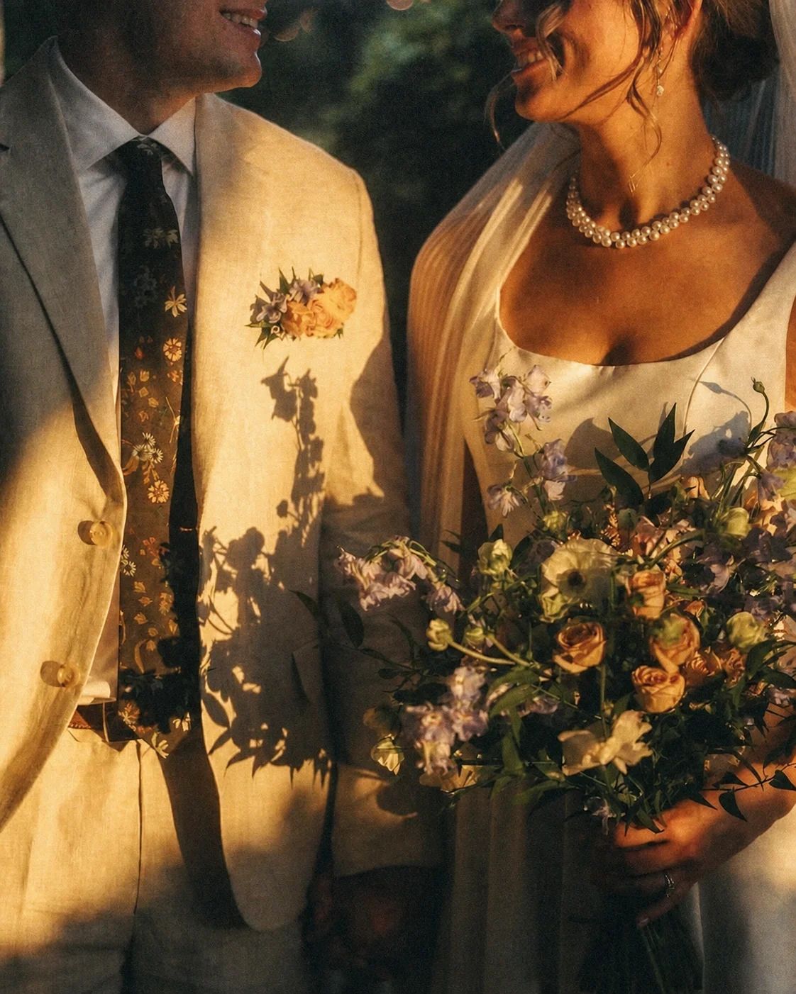 Bouquets and a boutonnière held close in golden hour light