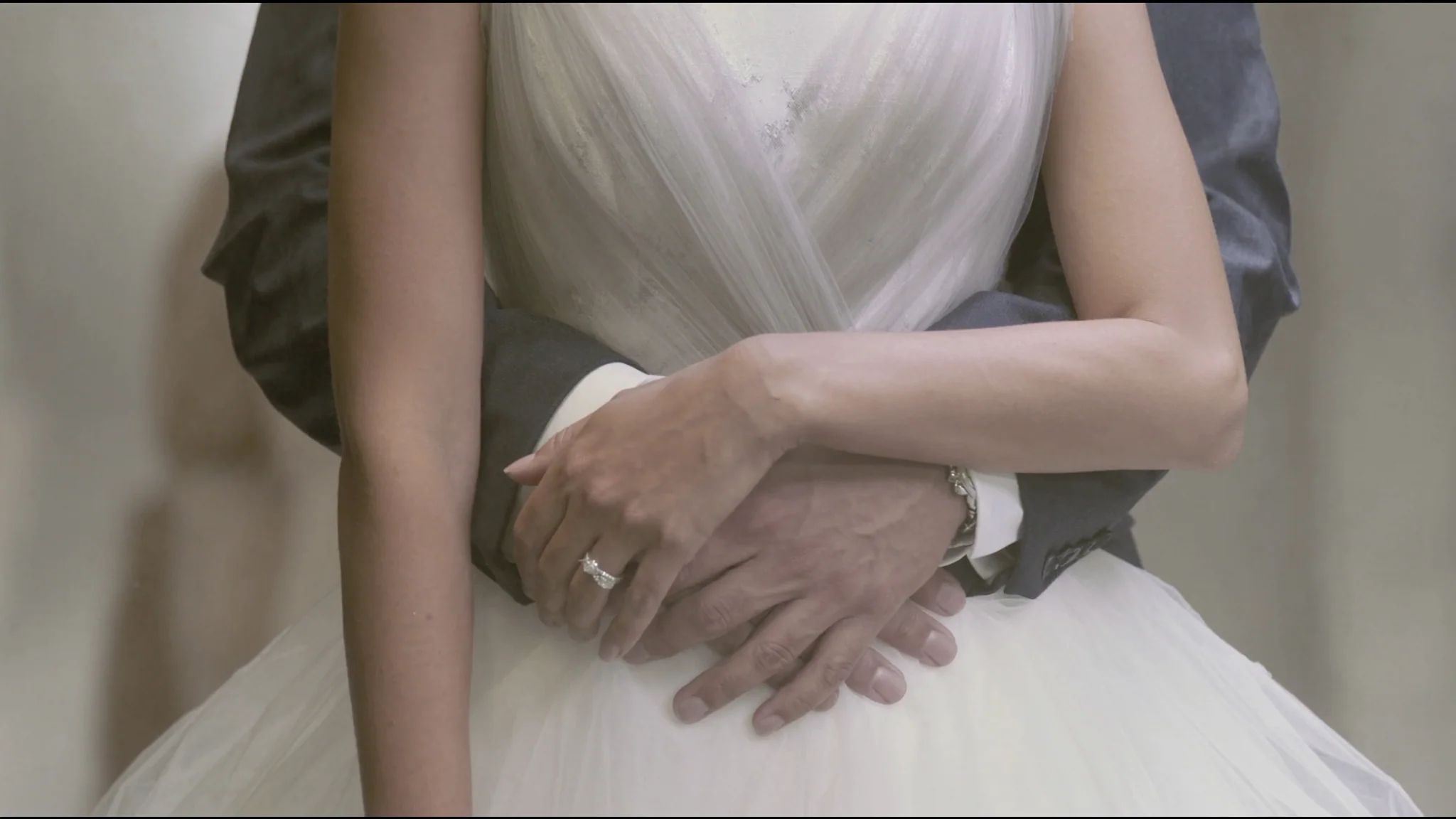 Hands and a wedding ring resting on a tulle skirt