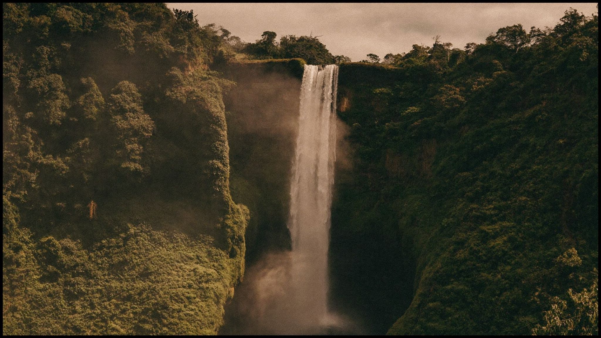 A waterfall deep in the rainforest with heavy green growth on both banks
