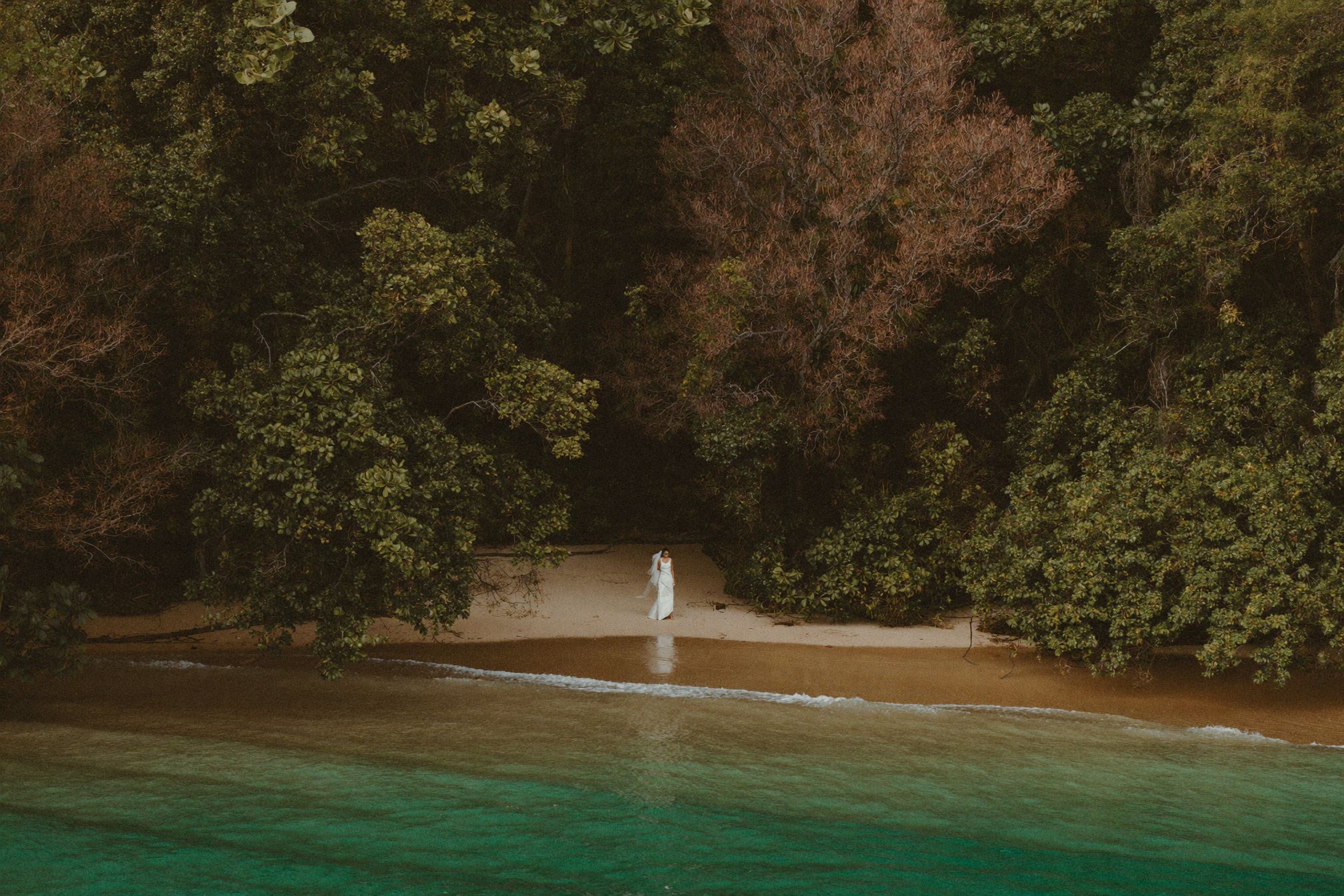 A turquoise cove at the end of the day with one figure on the sand