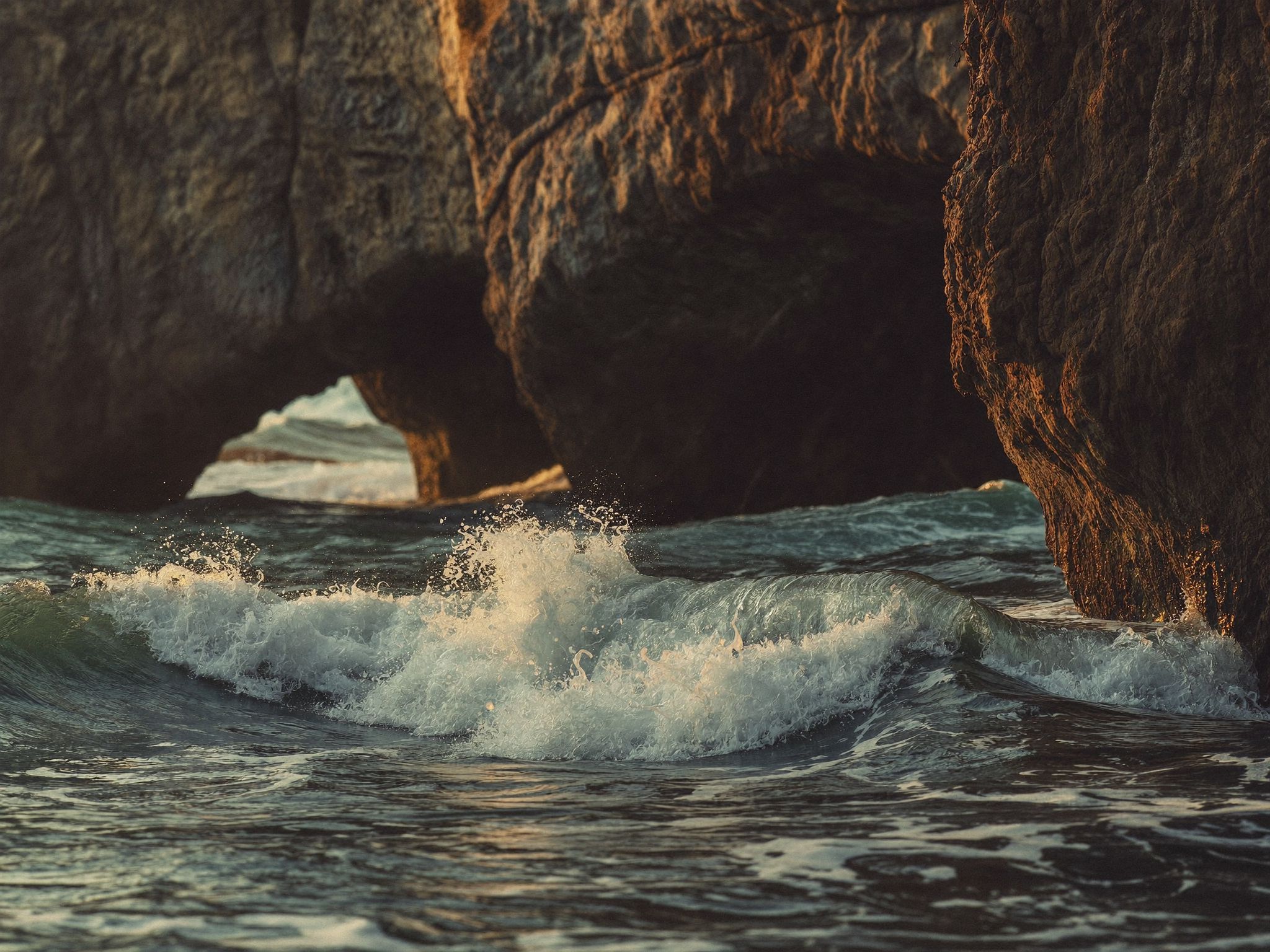 A sea arch with swell coming through it off the Pacific coast