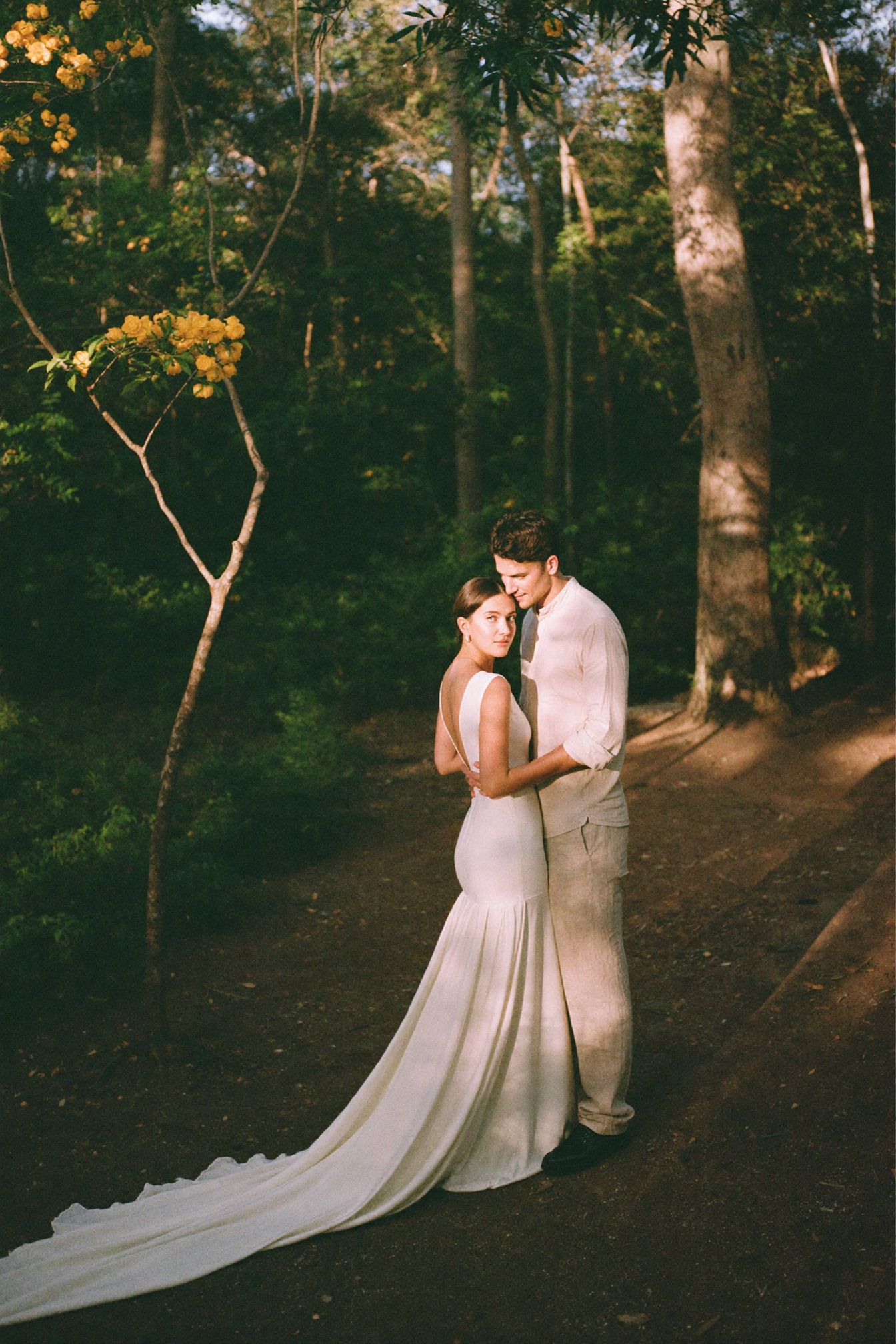 A couple standing close together in the forest at the end of the day