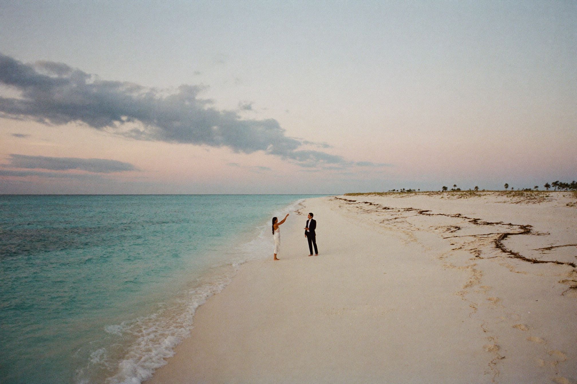 A couple saying vows barefoot on a white sand beach at sunrise in Cancún