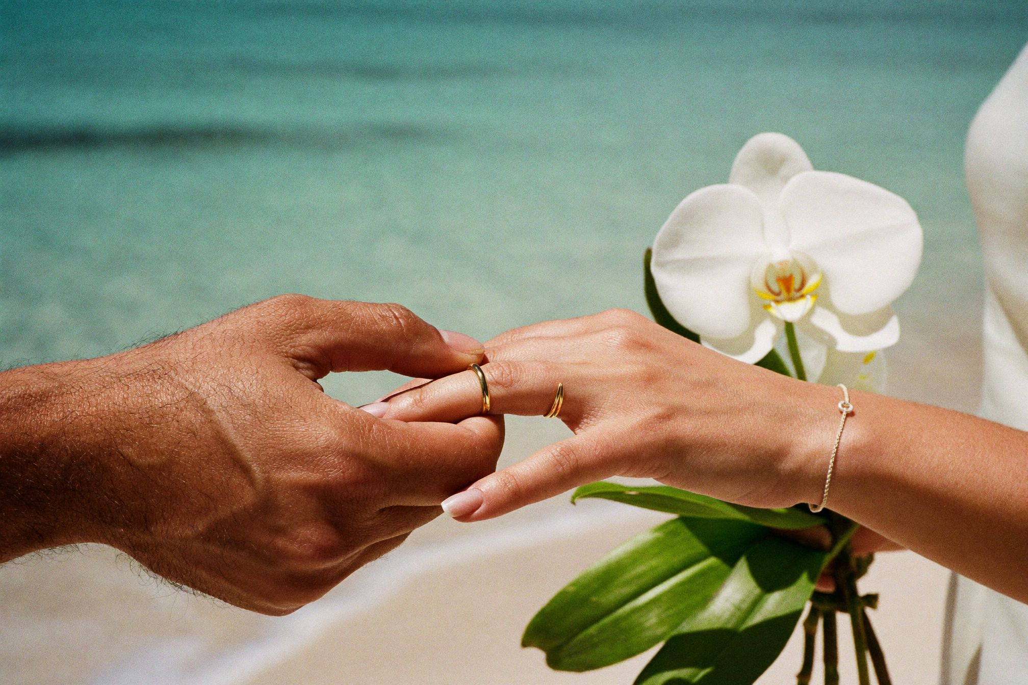 Two wedding bands photographed close up on pale sand