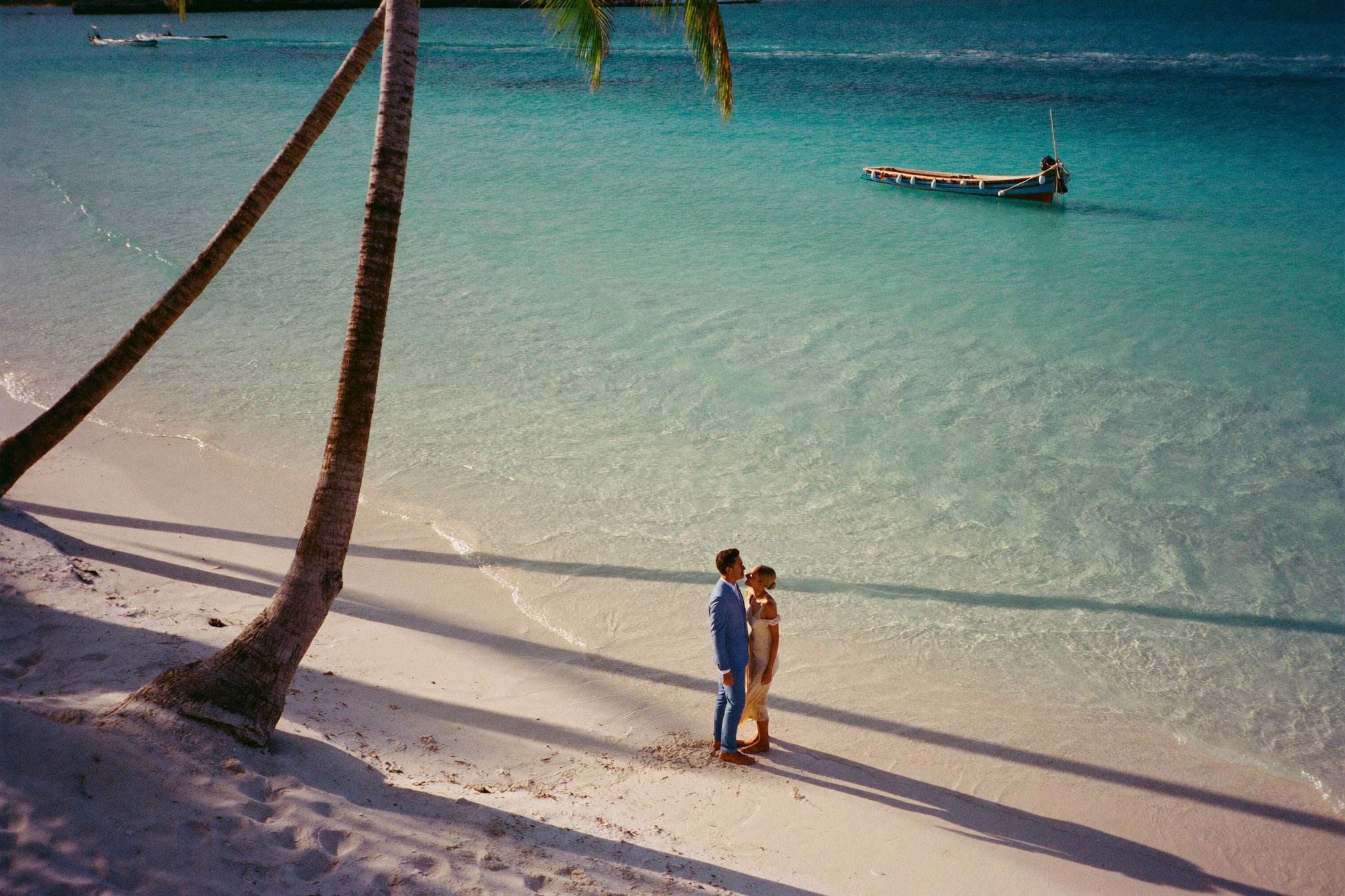 A small island coastline with pale turquoise shallows and palms