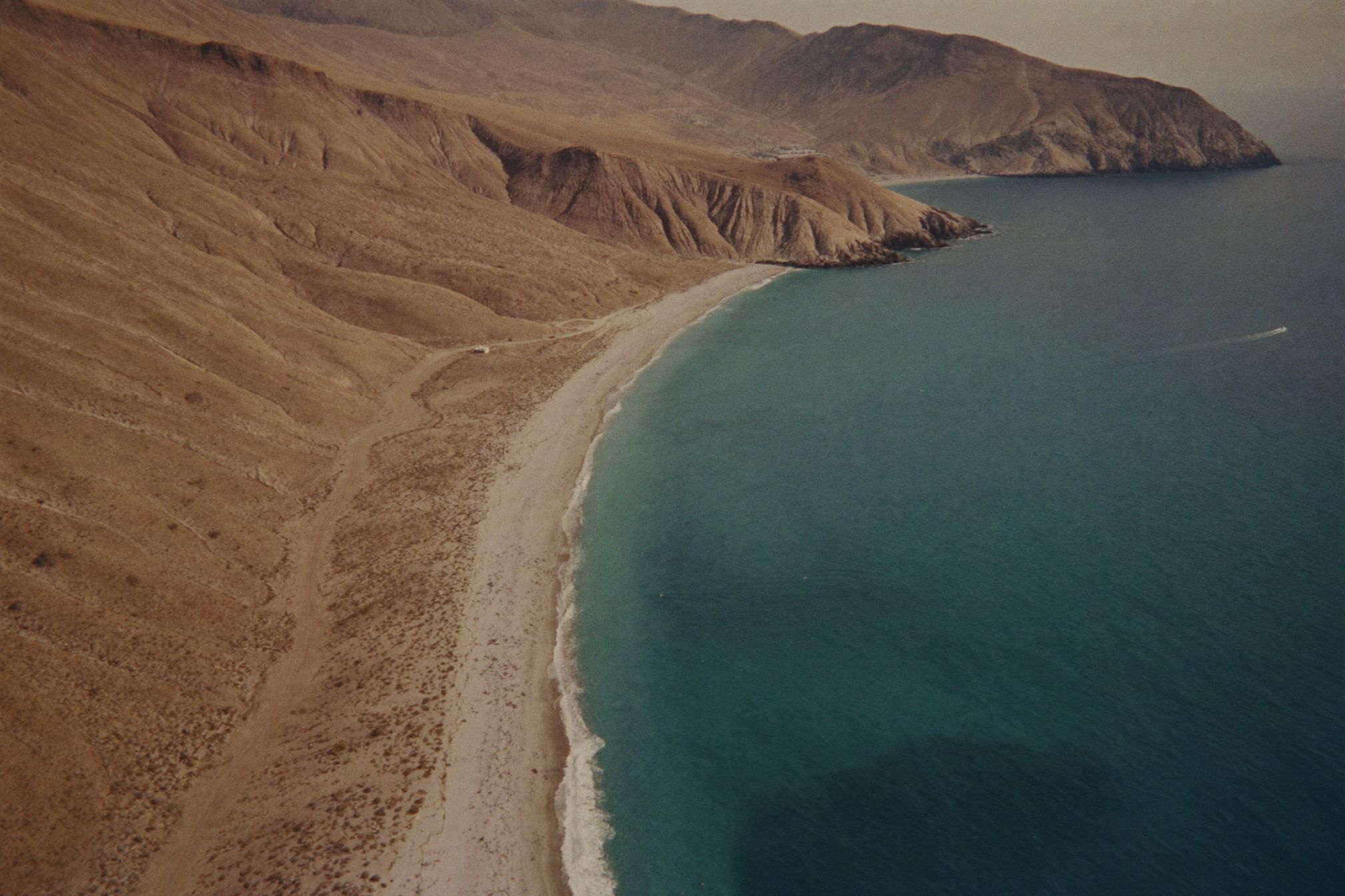 An aerial view of the Baja coastline with pale shallows and desert behind