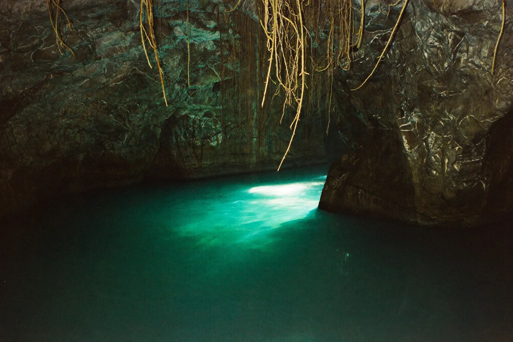 A freshwater cenote with light falling through an opening in the rock