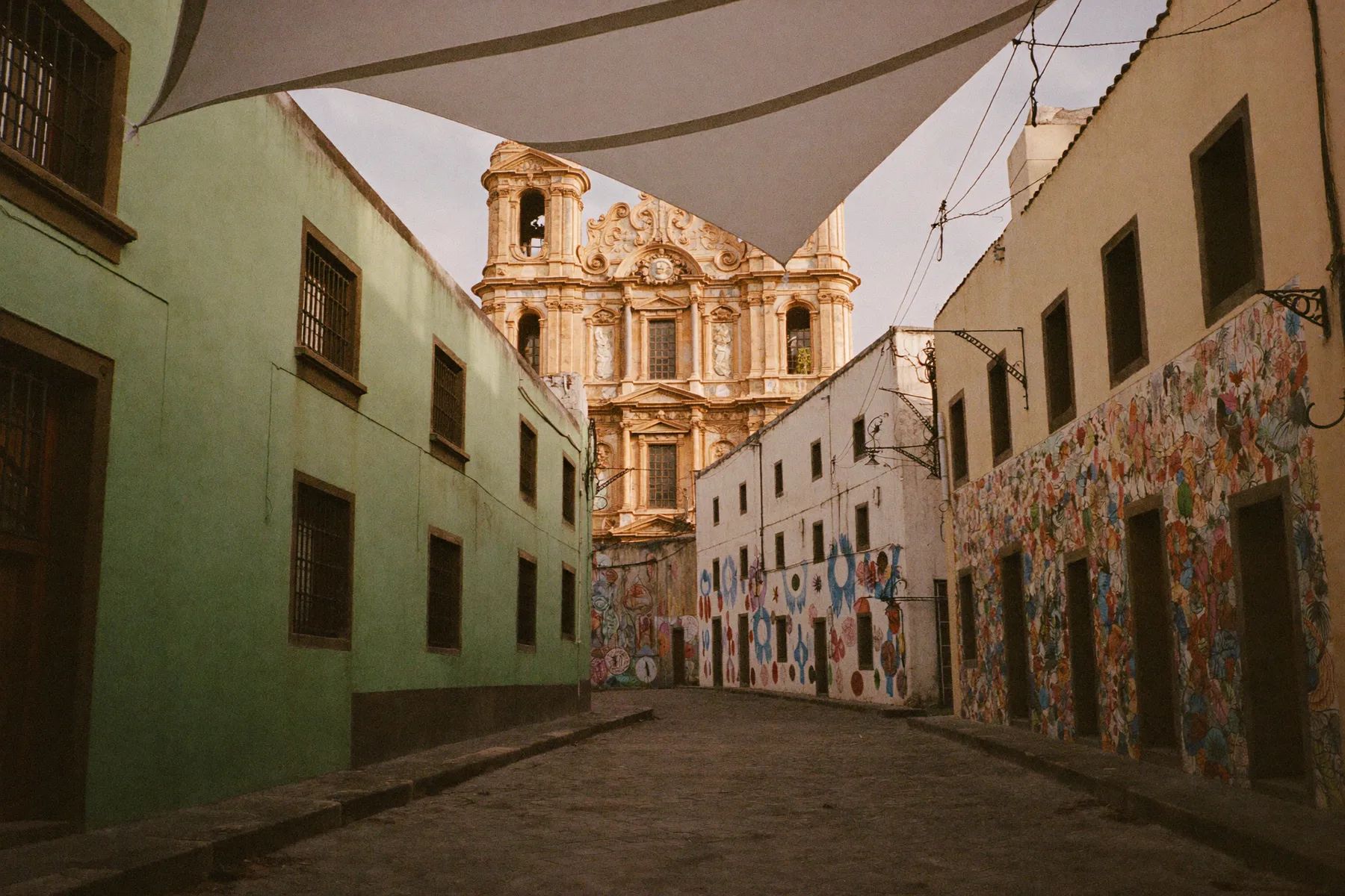 A cobbled street in the Jalatlaco quarter of Oaxaca with painted houses and a church at the end