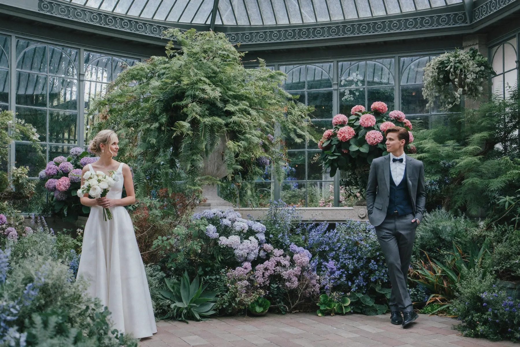 Bride and groom in the glasshouse of the Niagara Floral Showhouse, surrounded by hydrangeas