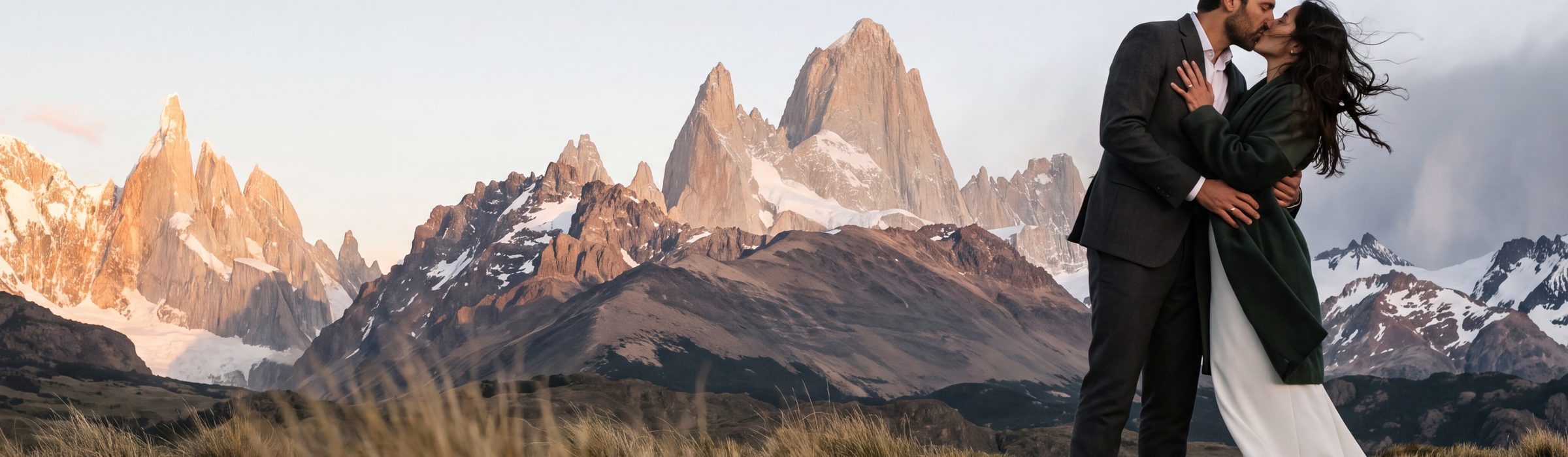 A couple kissing on a sheep track in the coirón steppe below the granite spires of Cerro Torre and Monte Fitz Roy, last evening light on the rock, El Chaltén | Arman Arai